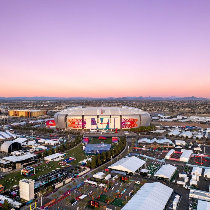 Aerial view of State Farm Stadium and surrounding event tents during a vibrant sunset in Glendale, Arizona.