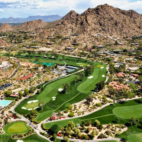 Aerial view of a scenic golf course in Paradise Valley, Arizona, with Mummy Mountain and the McDowell Mountains in the distance.