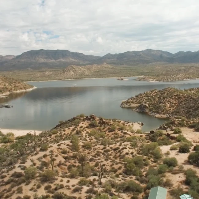 Aerial view of a desert reservoir surrounded by cactus-covered hills and distant mountains near Carefree, Arizona.