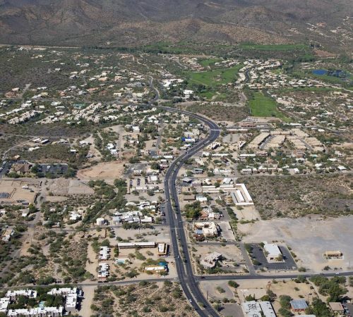 Aerial view of the desert town of Cave Creek, Arizona, featuring low-rise buildings, winding roads, and surrounding mountain hills.