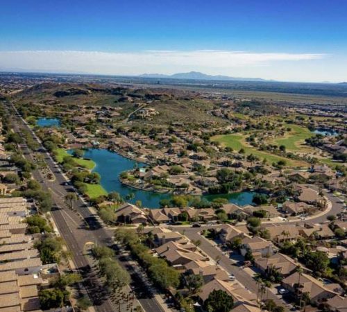 Aerial view of homes, lakes, and golf course greenbelts in the Ahwatukee Foothills neighborhood of Phoenix, Arizona, surrounded by desert mountains.