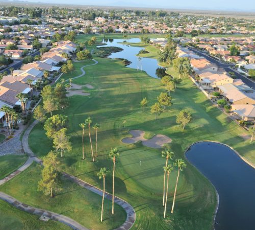 Aerial view of a lush golf course, lakes, and surrounding residential homes in the Sun Lakes retirement community in Arizona.