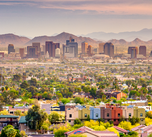 Elevated view of the Phoenix, Arizona downtown skyline and surrounding residential neighborhoods backed by mountains at sunset.