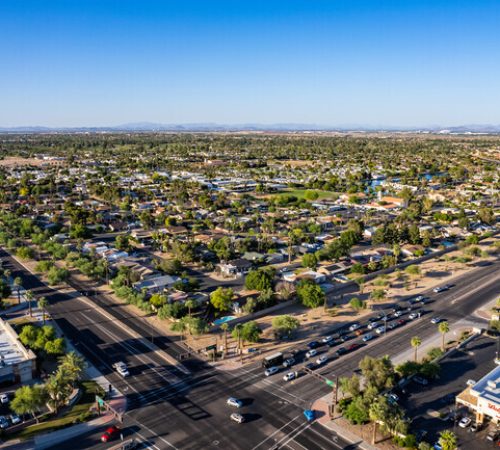 Aerial view of a tree-lined residential neighborhood, roadways, and commercial buildings in Litchfield Park, Arizona.