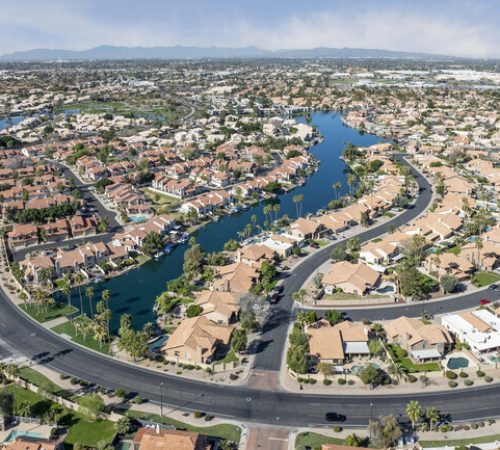 Aerial view of waterfront homes, winding lakes, and curving streets in The Islands neighborhood of Gilbert, Arizona.